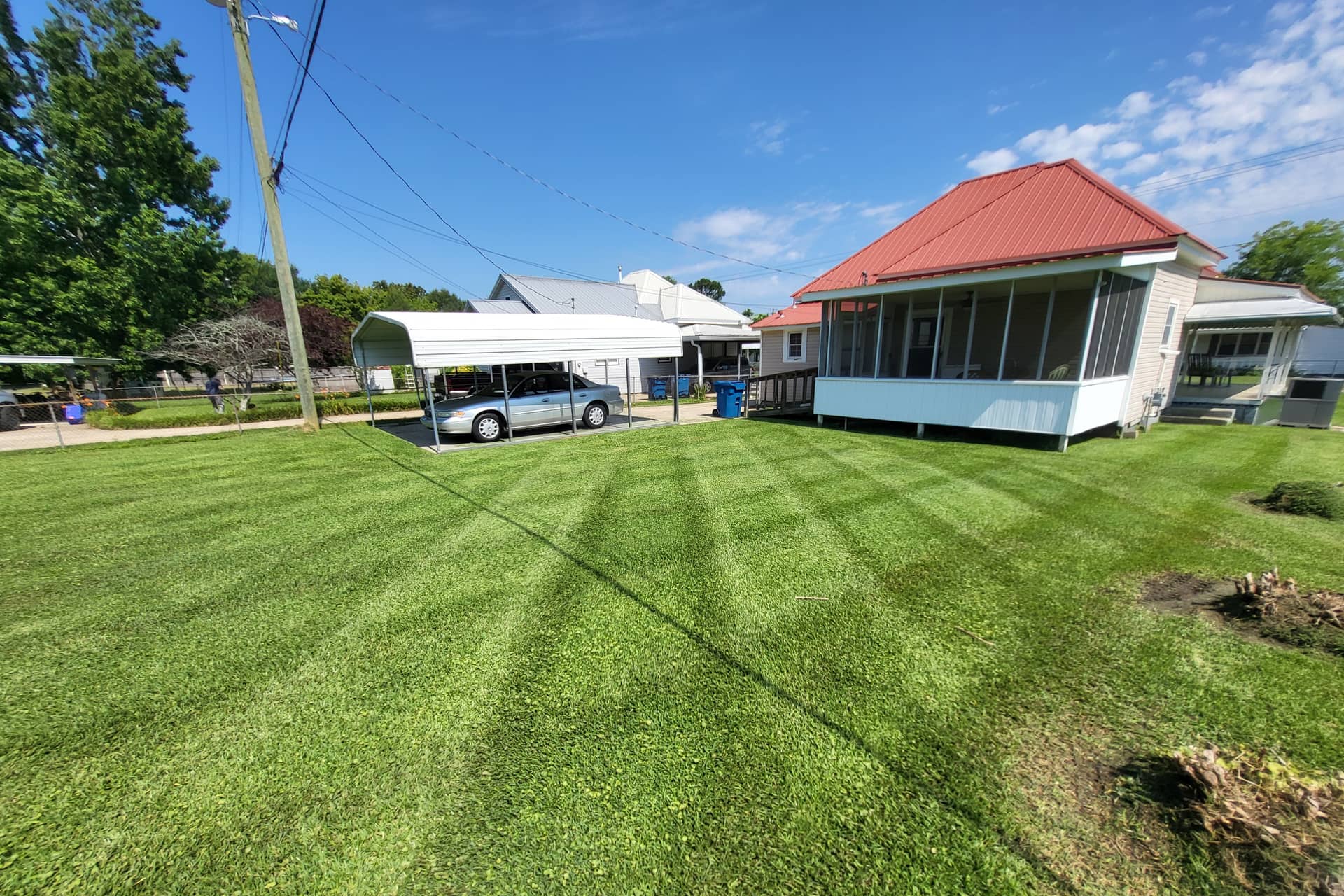 A freshly mown back lawn with crisp diagonal stripes beside a red-roofed house