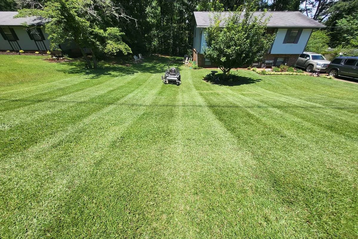 A riding mower on a cleared, freshly striped lawn